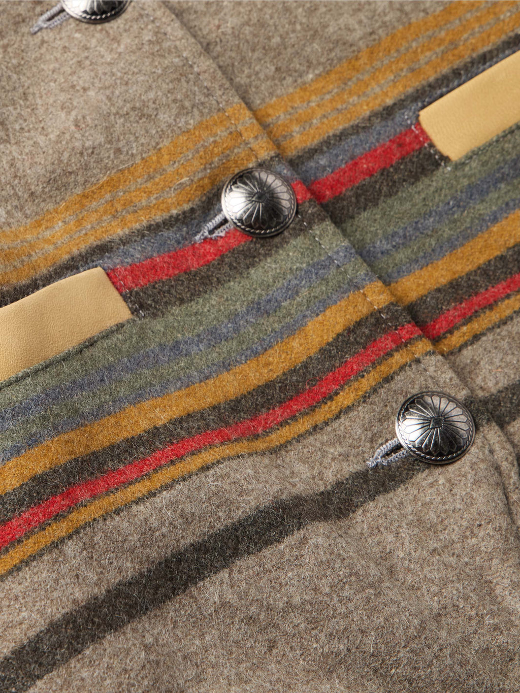Close-up of taupe striped jacket fabric with multicolor bands and round metal snaps