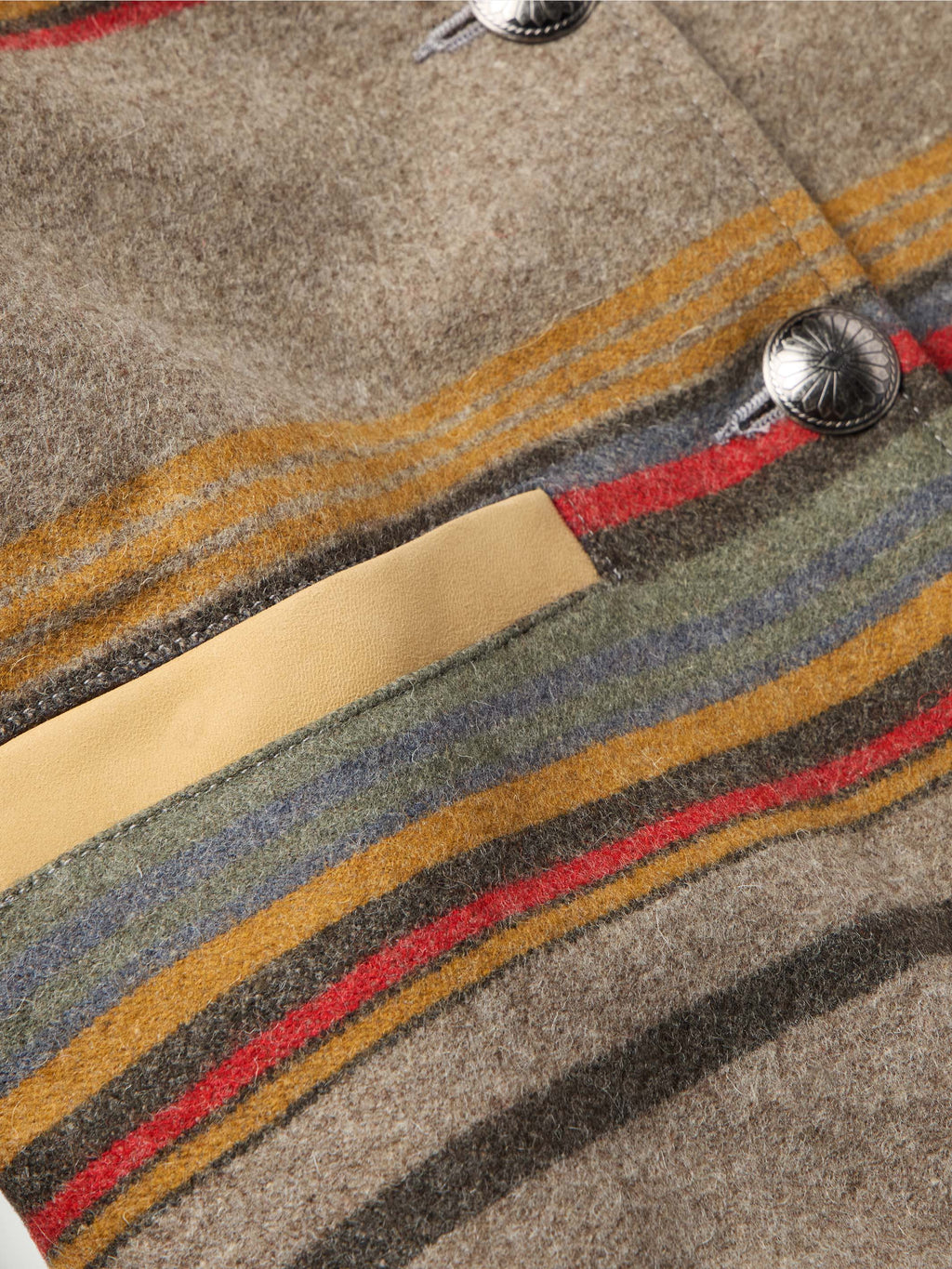 Close-up of taupe striped jacket with tan cuff and round metal snaps