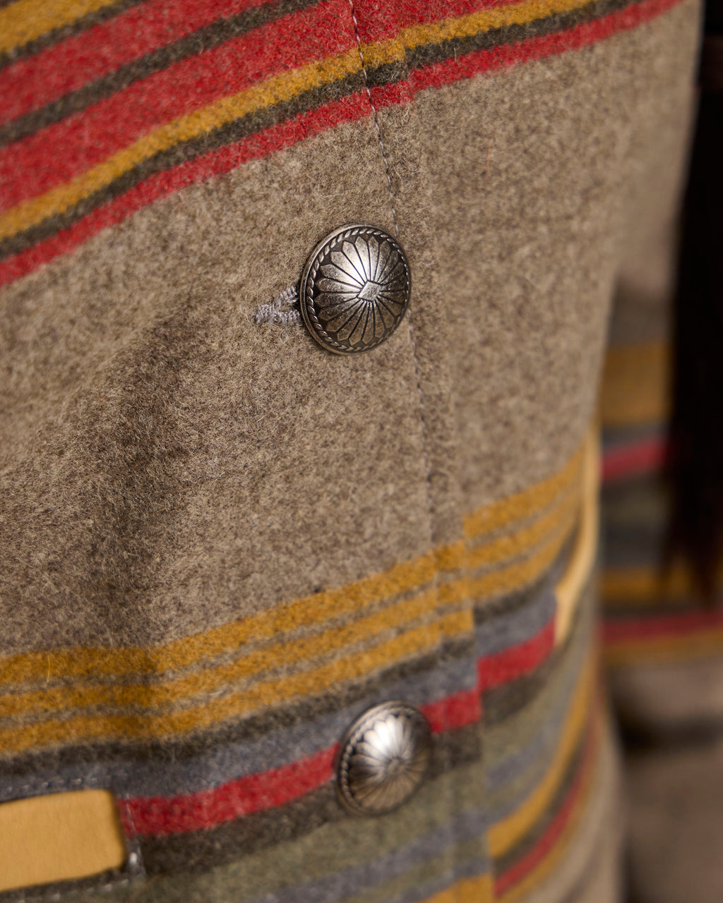 Close-up of jacket button and striped fabric panel on taupe wool