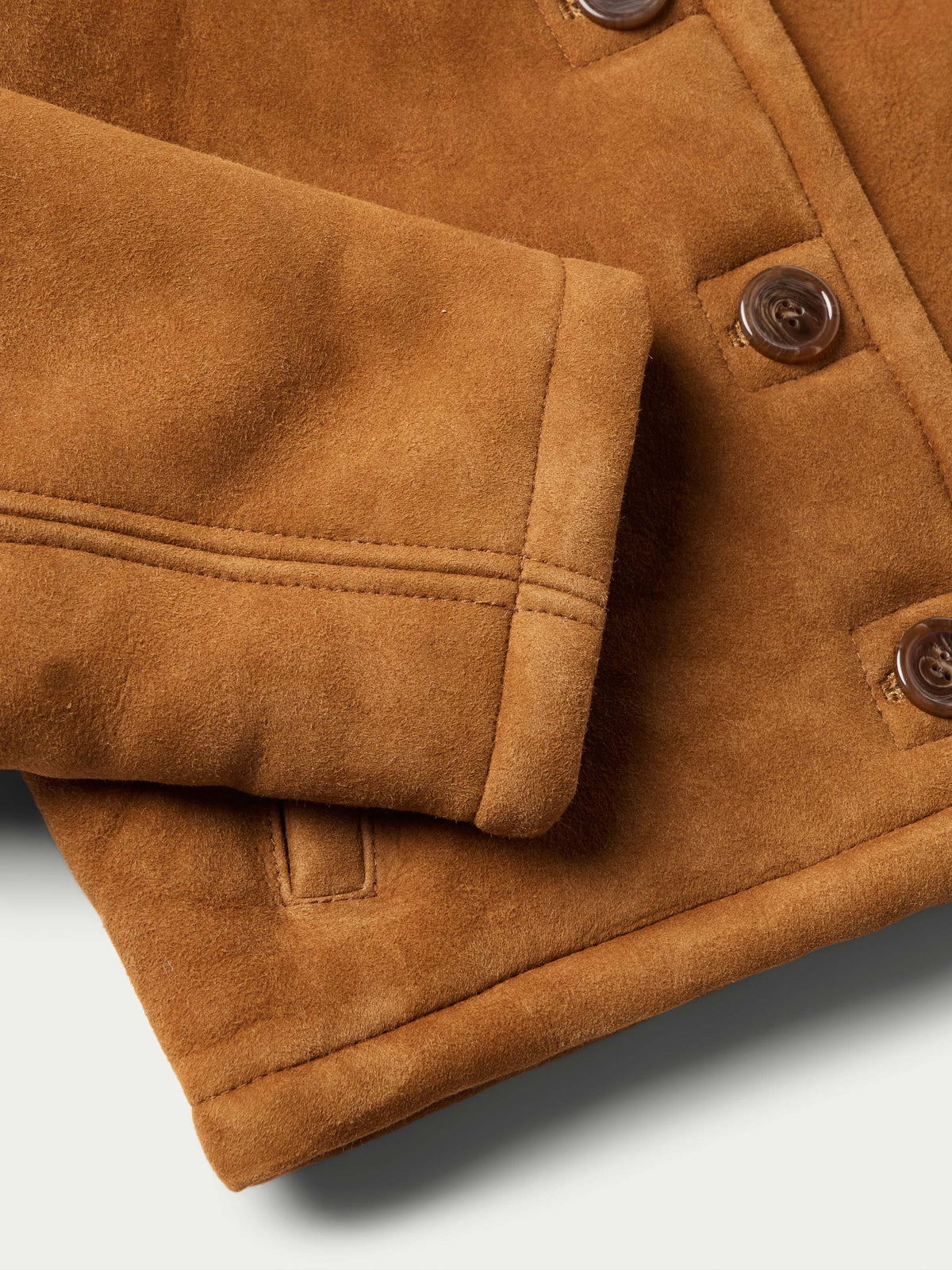 Close-up of brown shearling jacket cuff with stitched placket and buttons