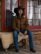 Brown shearling jacket worn outdoors with black wide-brim hat and jeans