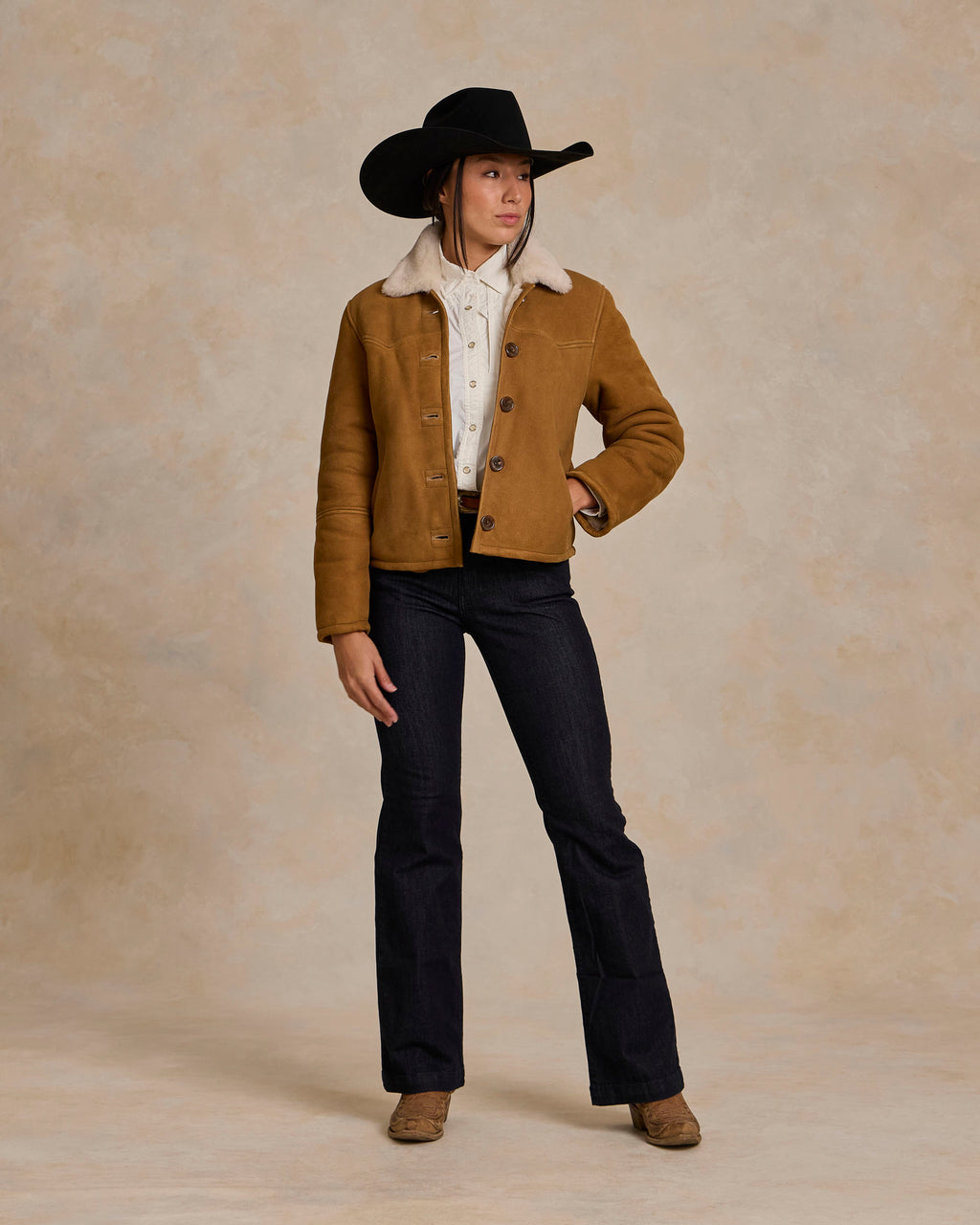 Brown shearling jacket with tan sherpa collar over a light shirt and dark pants