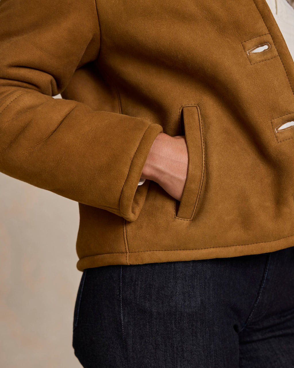 Brown shearling jacket sleeve and side hand-warmer pocket with seam stitching