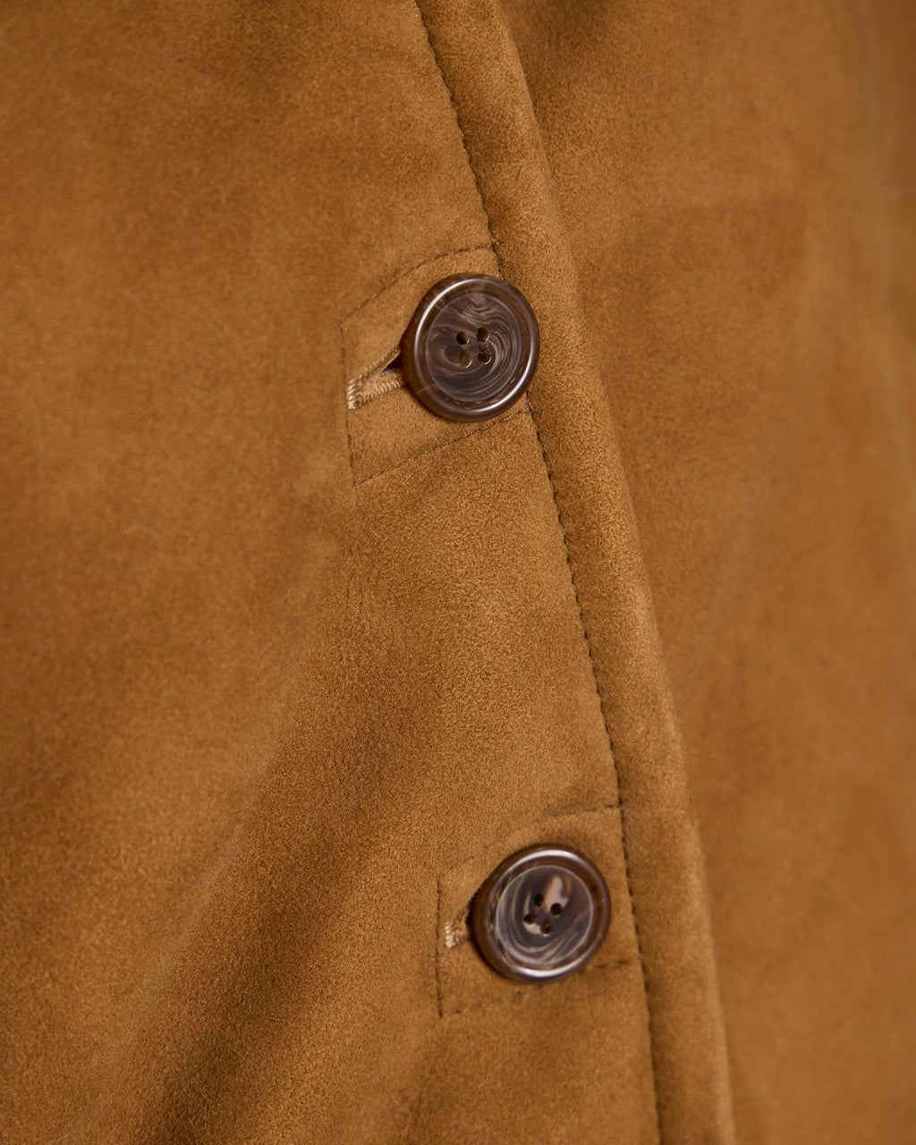 Brown shearling jacket fabric close-up with round button and topstitching