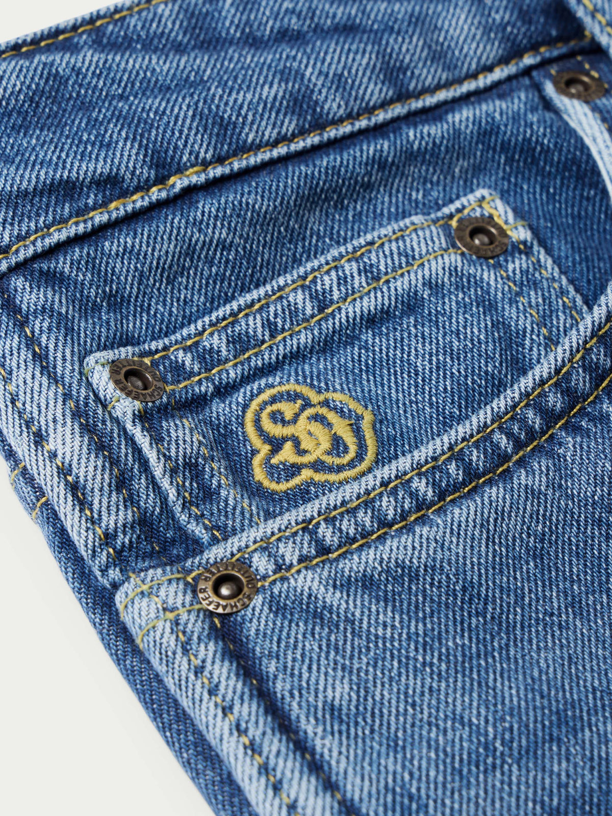 Medium indigo jeans with decorative yellow yoke stitching and metal button detail