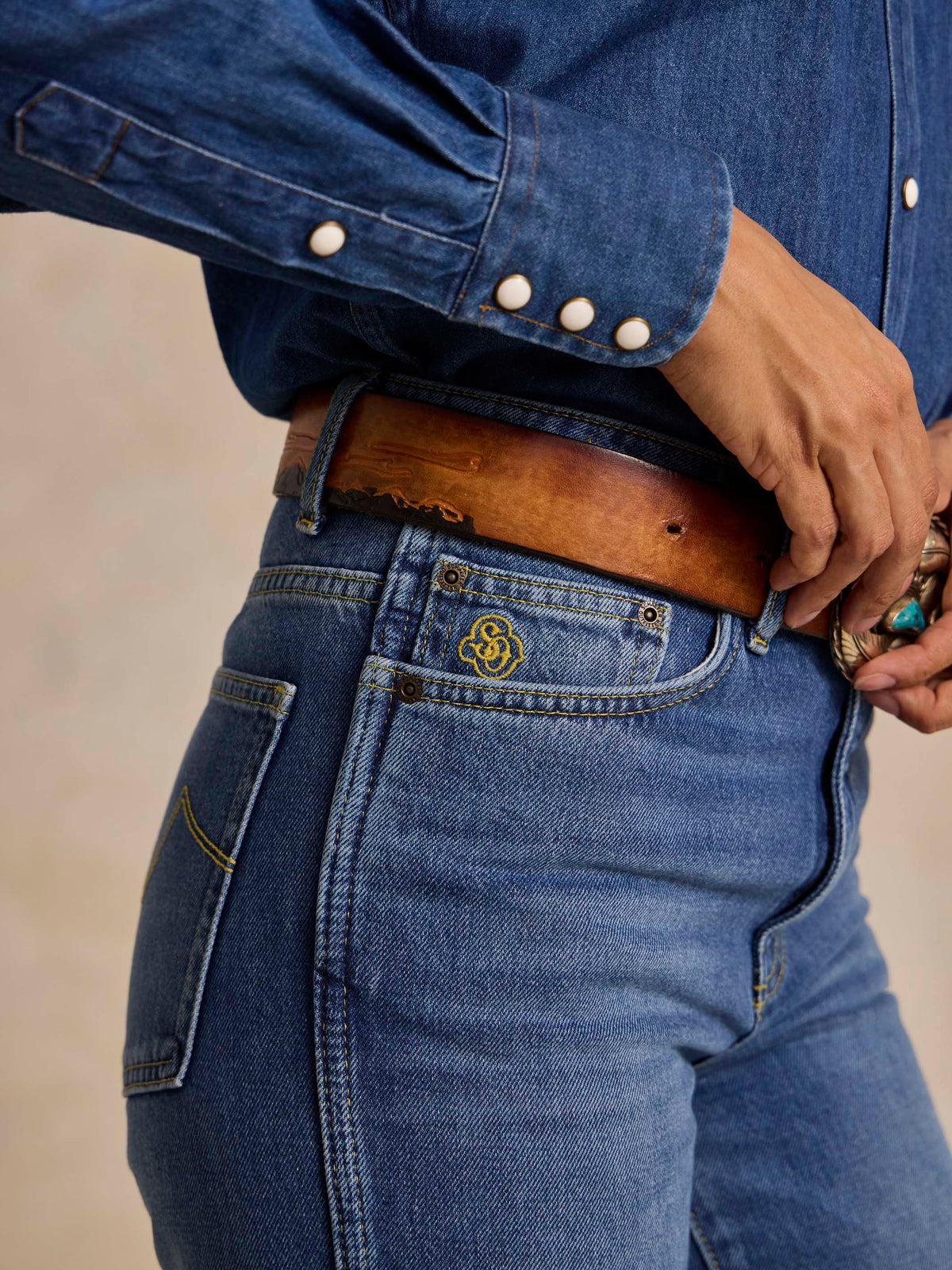 Medium indigo jeans waistband detail with belt loops, button closure and stitched back yoke