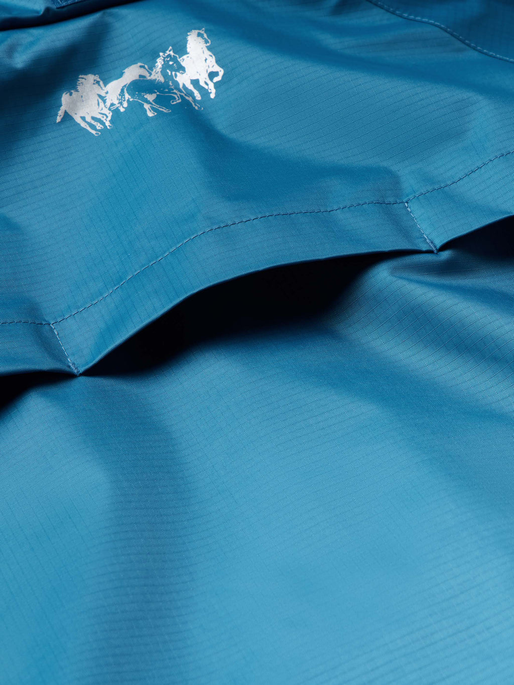 Baltic blue rain jacket fabric close-up with stitched seams and textured weave