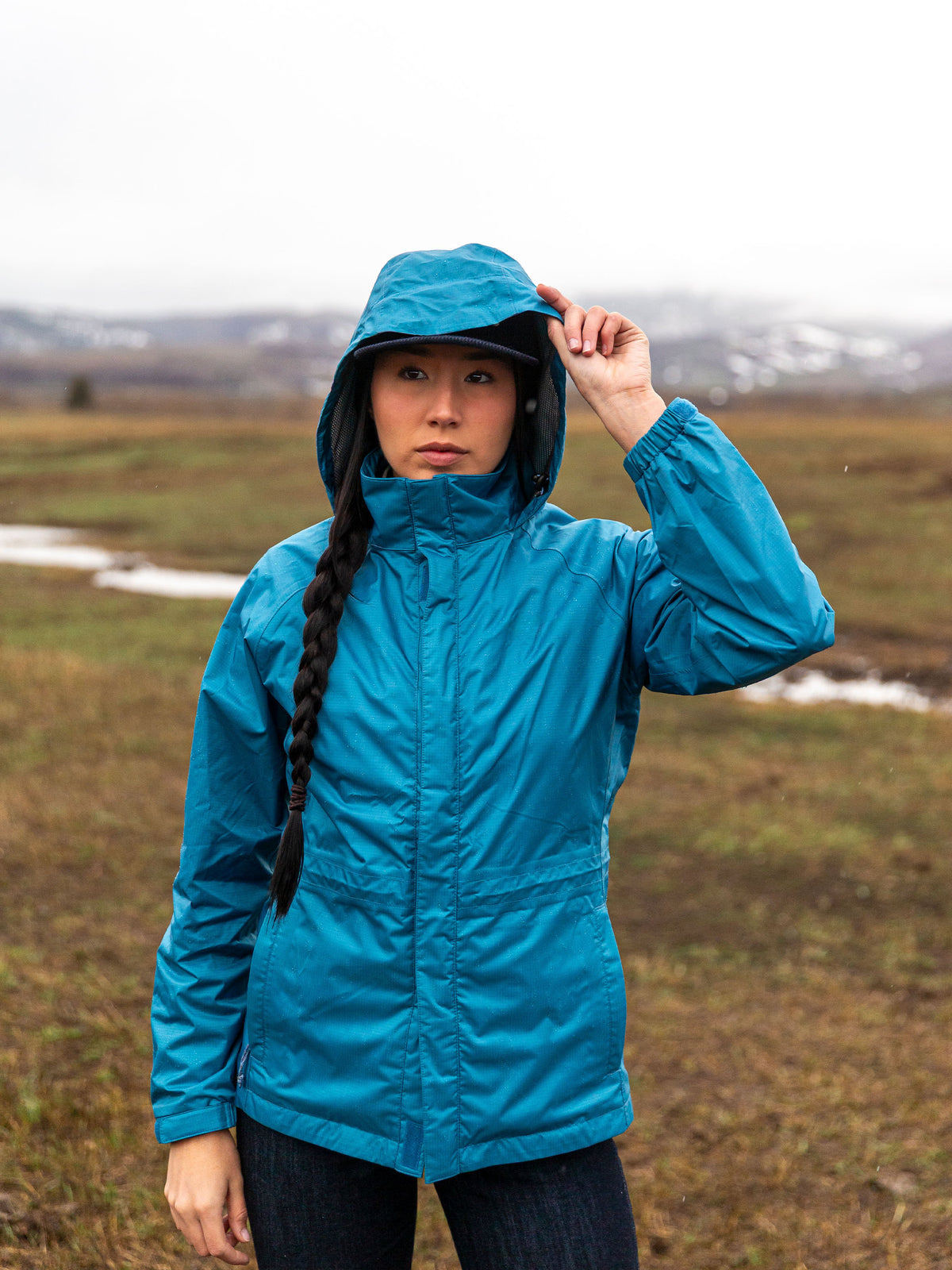 Blue hooded rain jacket with zipper front and drawstring hood, front view