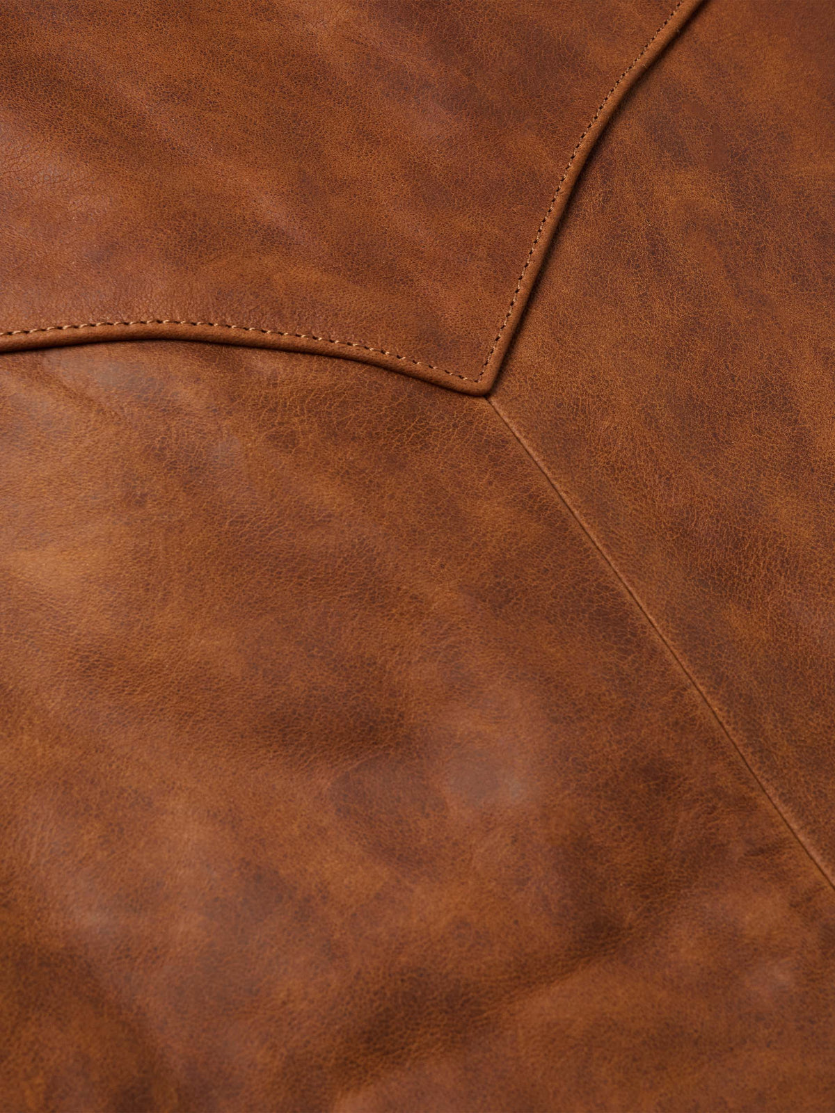 Close-up of whiskey-brown leather vest with contrast topstitching and seams