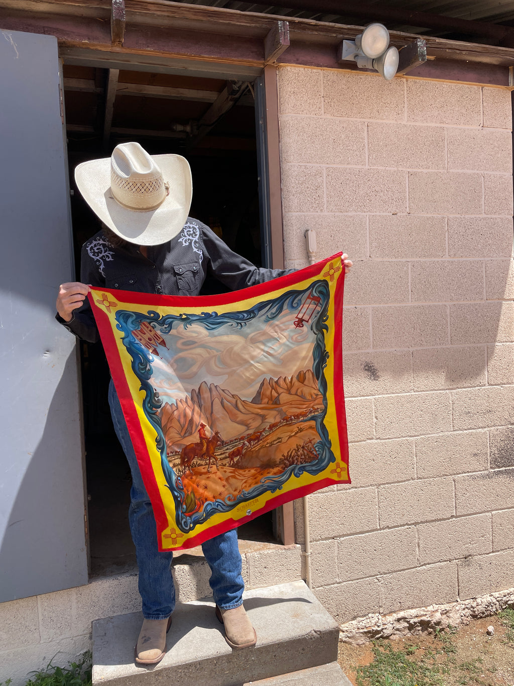 Wild rag scarf held in front with blue border and desert horses scene