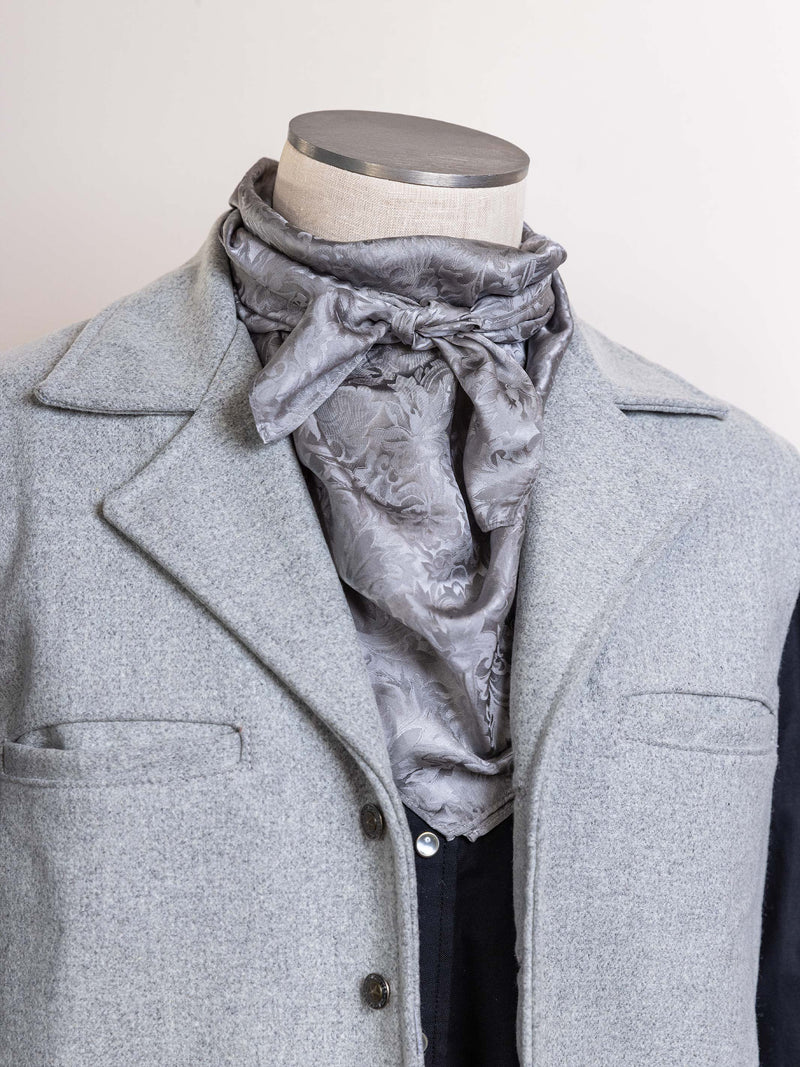 Silver jacquard wild rag scarf with draped neck tie, worn under a coat