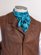 Turquoise jacquard wild rag scarf tied at neckline with bow and gathered folds