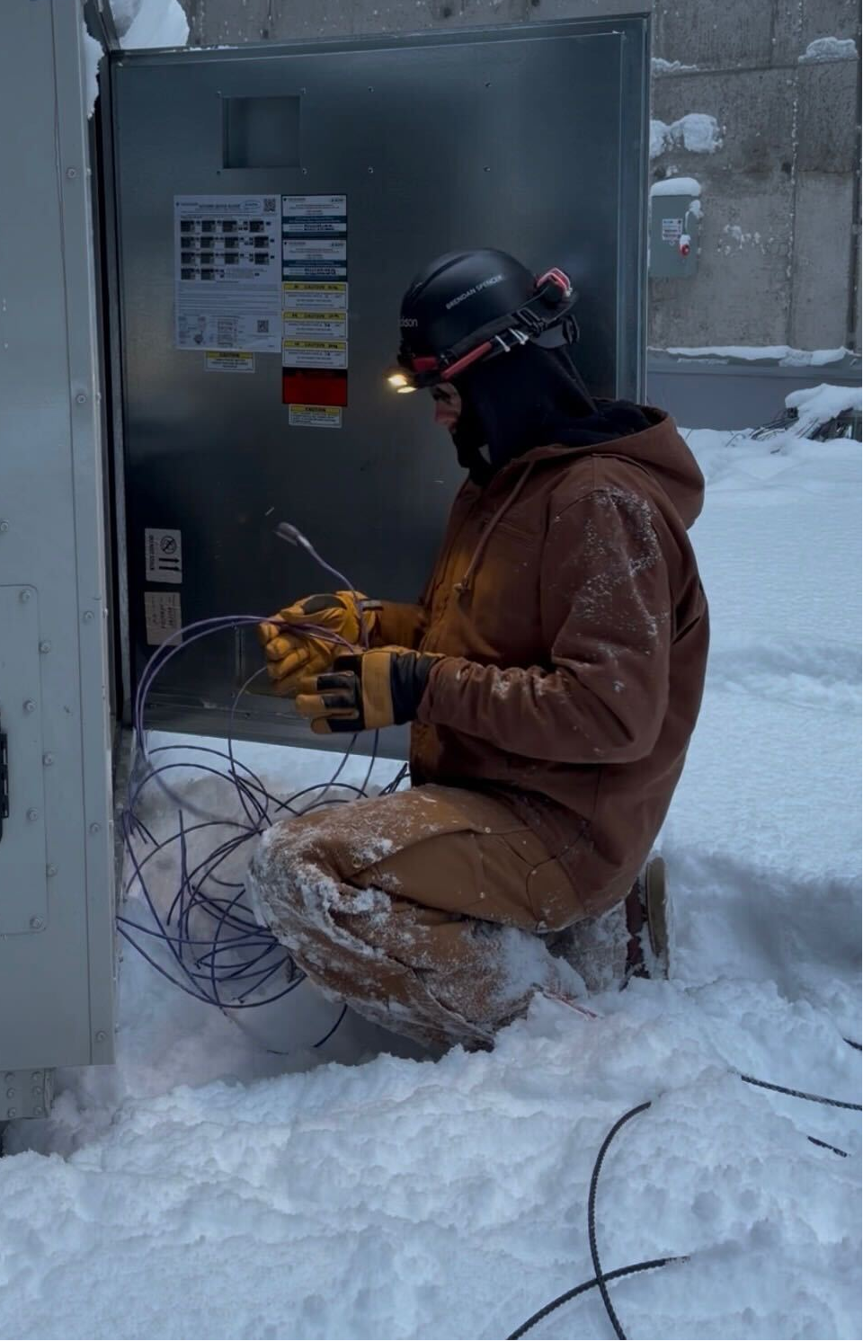 Person working on electrical equipment in a snowy outdoor setting