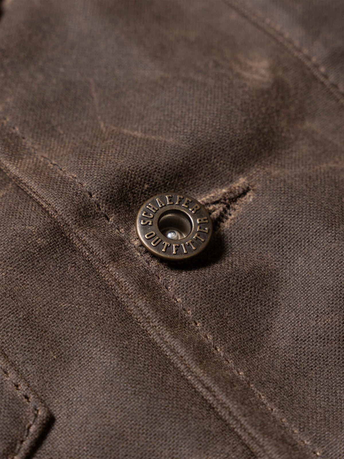 Mesquite vest button detail on dark brown fabric with stitched seam
